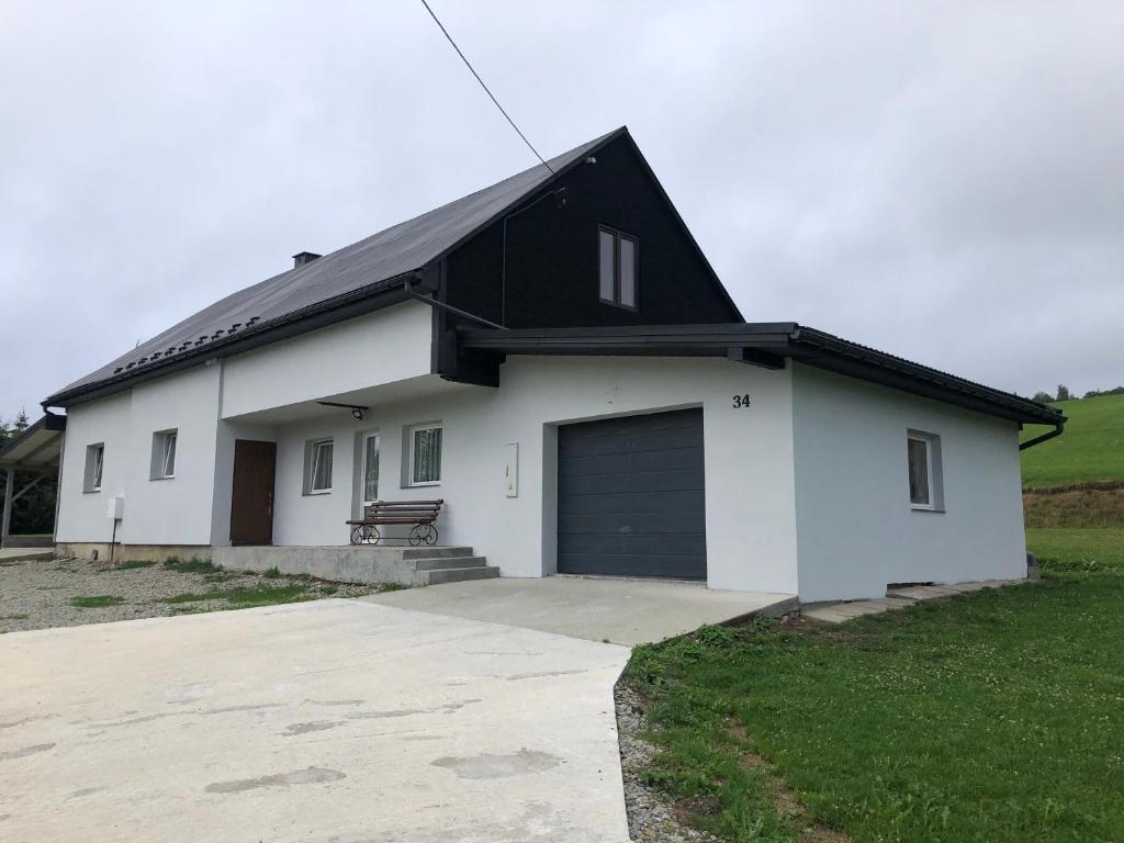 a white house with a black roof and a garage at Domek Ranczo in Mochnaczka Wyżna