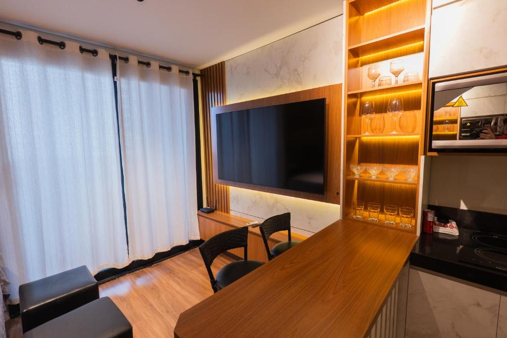 a hotel room with a table and a flat screen tv at Flat Exclusivo studio cuiaba 702 in Cuiabá