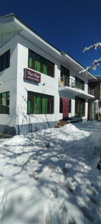 a white building with snow in front of it at Tip Top Pahalgam in Pahalgām