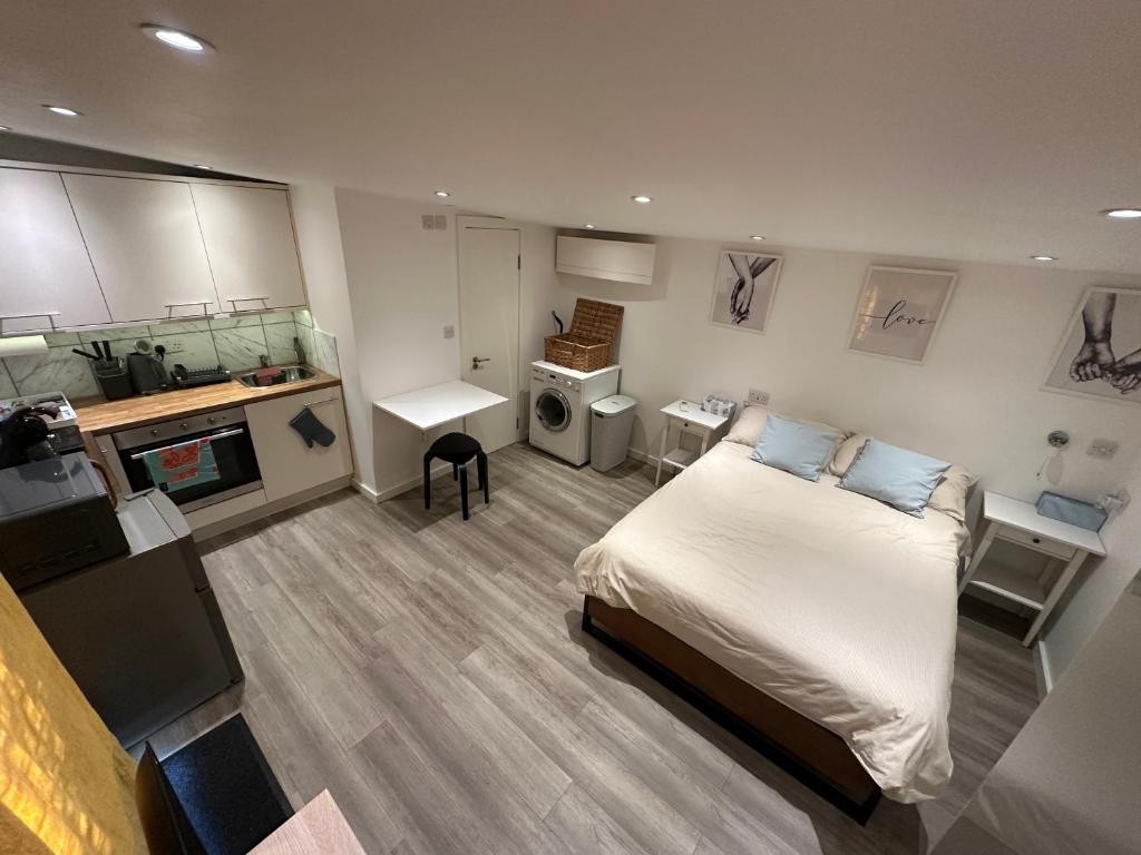 a small bedroom with a bed and a kitchen at Cosy, self-contained guest house in Thornton Heath