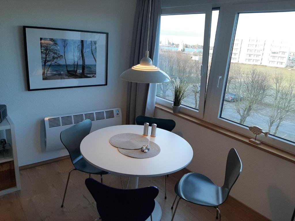 a white table and chairs in a room with windows at Möwenhorst in Fehmarn