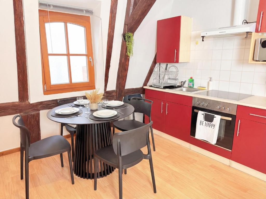 a kitchen with red cabinets and a table and chairs at Le Cocon Alsacien au cœur de Rouffach in Rouffach