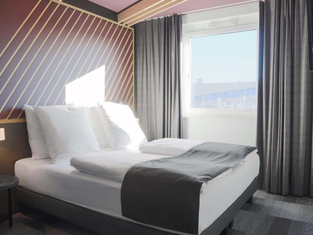 a bed in a hotel room with a window at B&B Hotel Böblingen in Böblingen