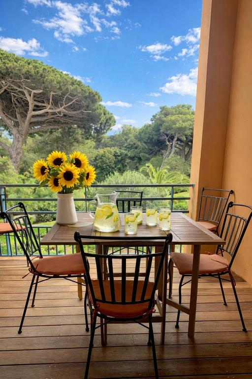 a table with chairs and a vase of sunflowers on a deck at LA BADINE Appartement 5 personnes avec balnéo et clim in Hyères