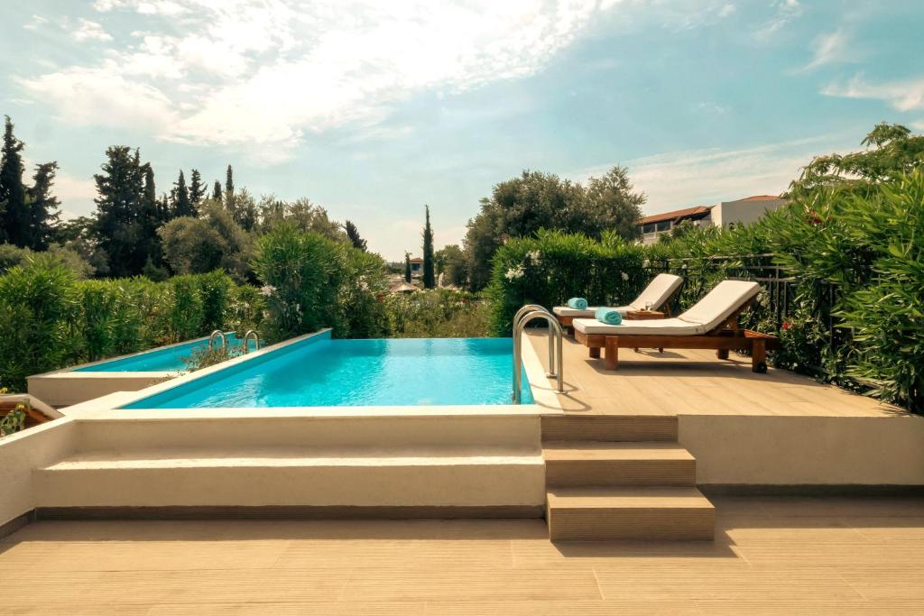 a swimming pool in a garden with a bench next to a swimming pool at Zeus Eretria Resort in Eretria