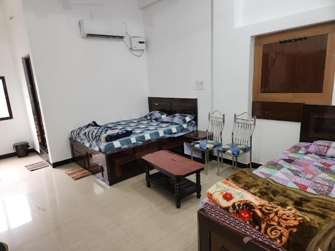 a room with two beds and a table and chairs at Om Hotel & Lodge in Baharāgora