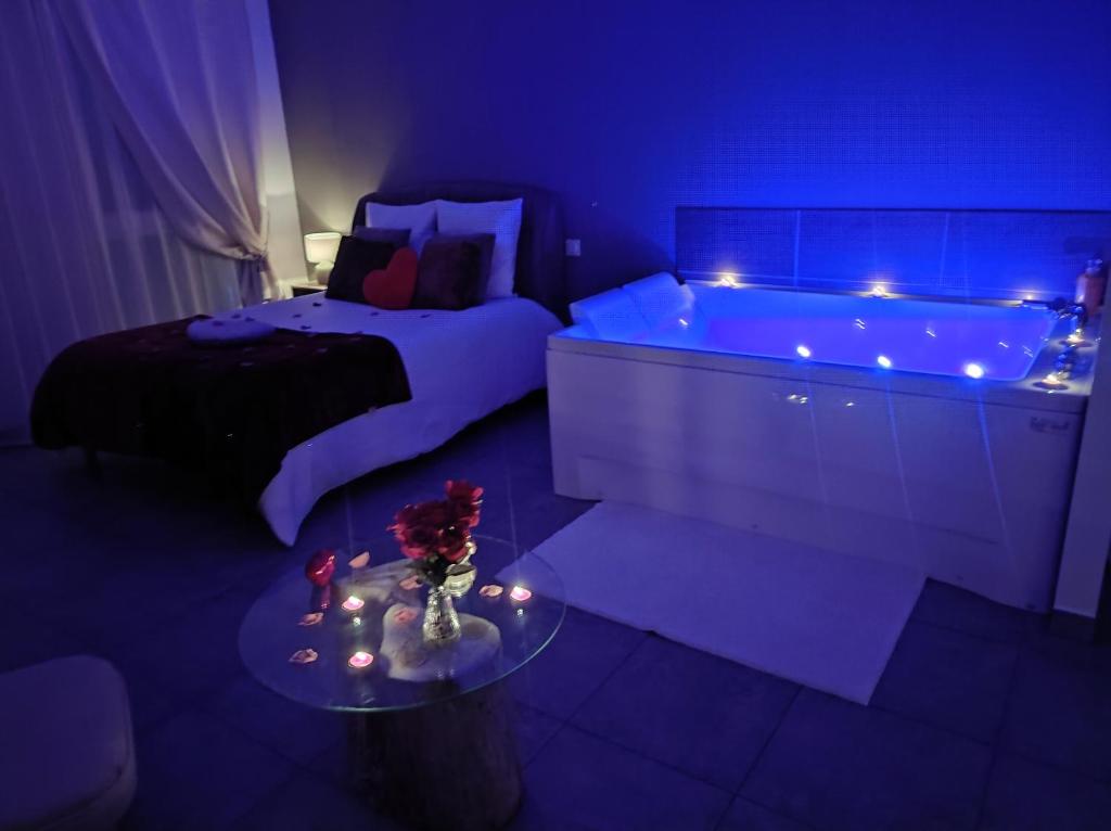 a bedroom with a bed and a tub with lights at La chambre des tentations , love room avec jacuzzi in Bages