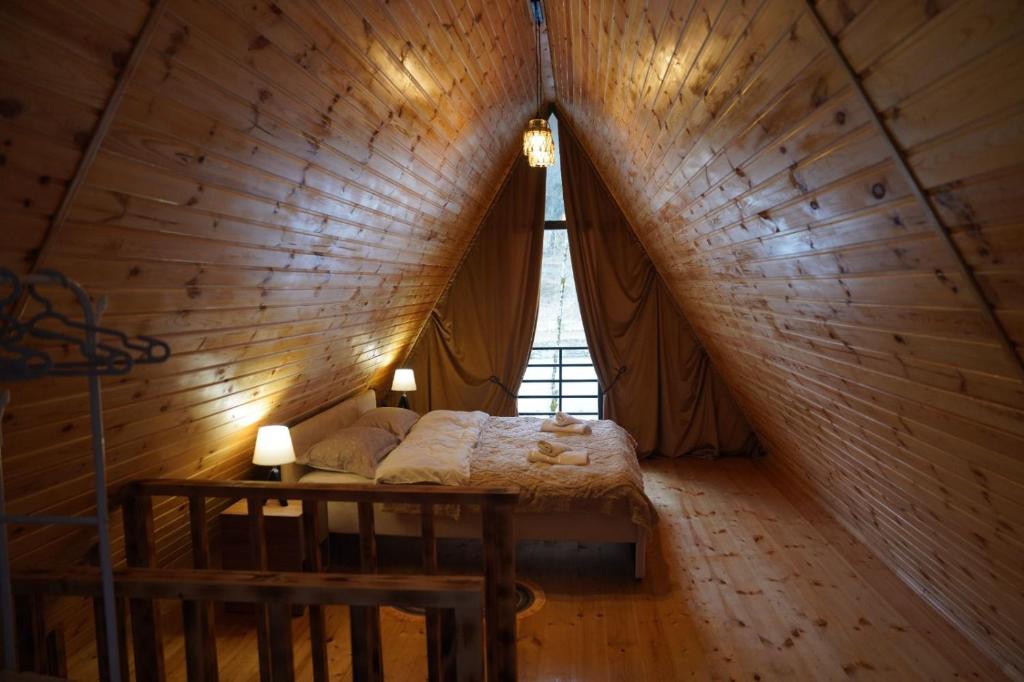 un letto in una stanza di legno con una finestra di Machakhela Hills a Machakhlispiri