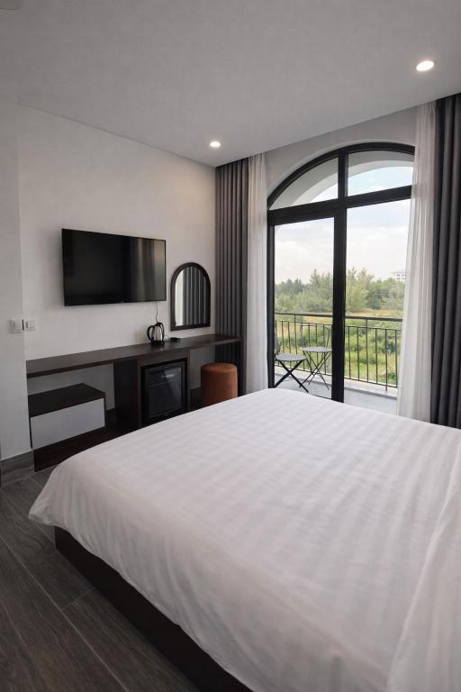 a bedroom with a large white bed and a window at Tom Tom Homestay in Phú Quốc
