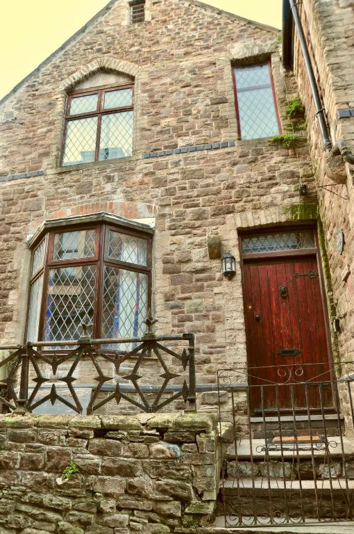 a brick building with a red door and two windows at Ash Cottage - Caerleon in Newport