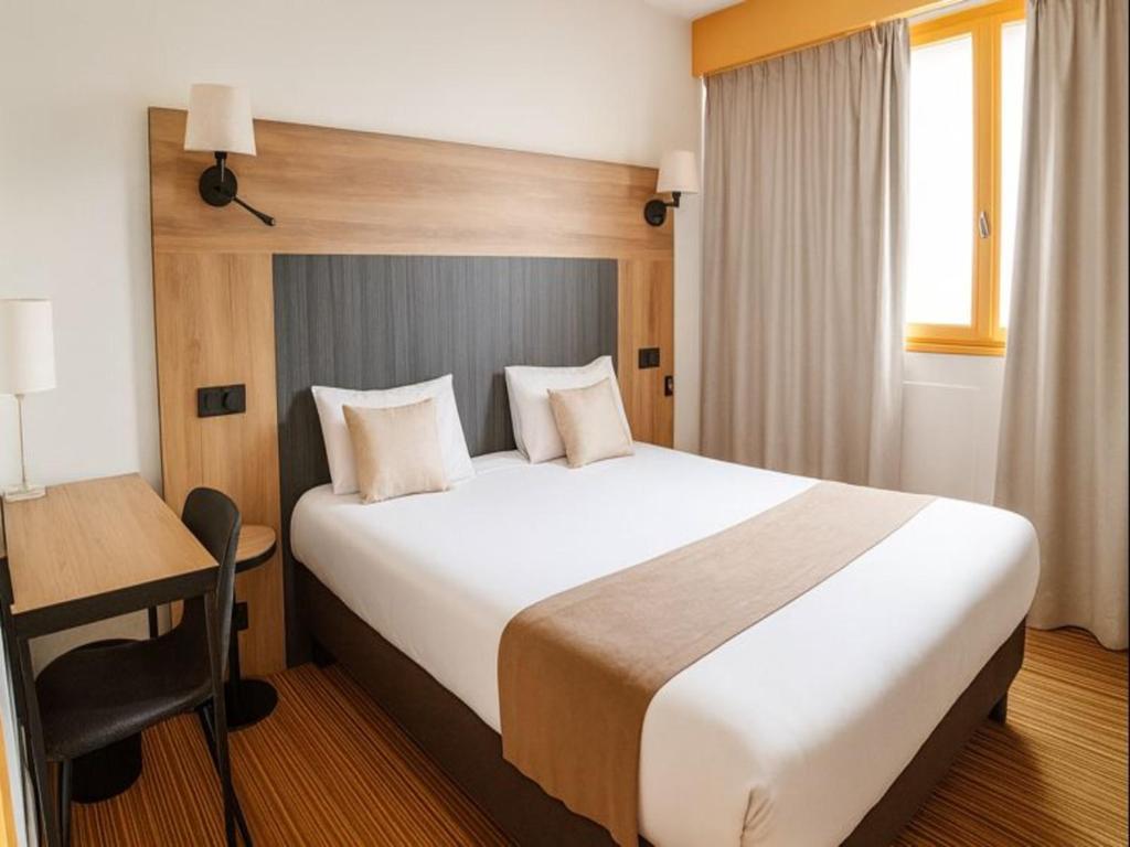 a hotel room with a large bed and a desk at The Originals City, Hôtel Napoléon, La Roche-sur-Yon in La Roche-sur-Yon