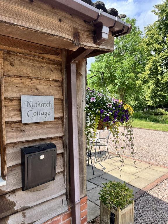 a sign on the side of a building with flowers at LODGE Nuthatch in Droitwich