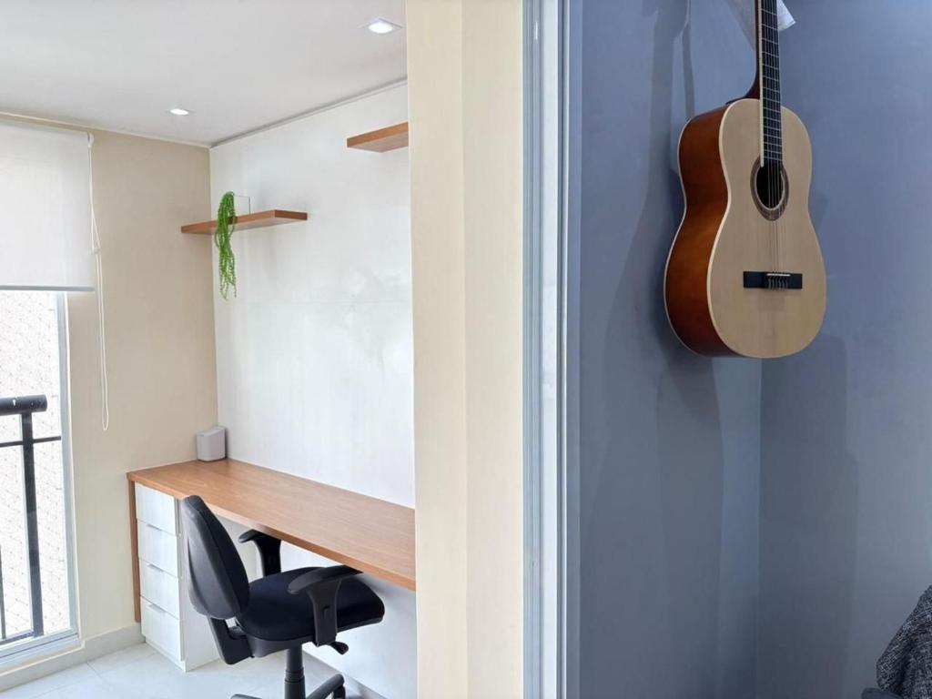 a guitar hanging on a wall next to a desk at 1506 - studio novo e completo in Guarulhos