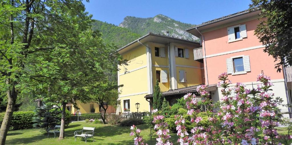 a yellow and pink building with flowers in a yard at Albergo Silvana in Ledro