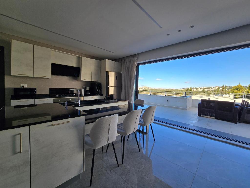 a kitchen with white chairs and a large window at Villa rooftop with stunning view apartment in Amman