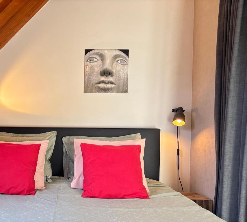 a bed with red pillows and a picture of a face at Gastenverblijf Chambre dAmis in Heers