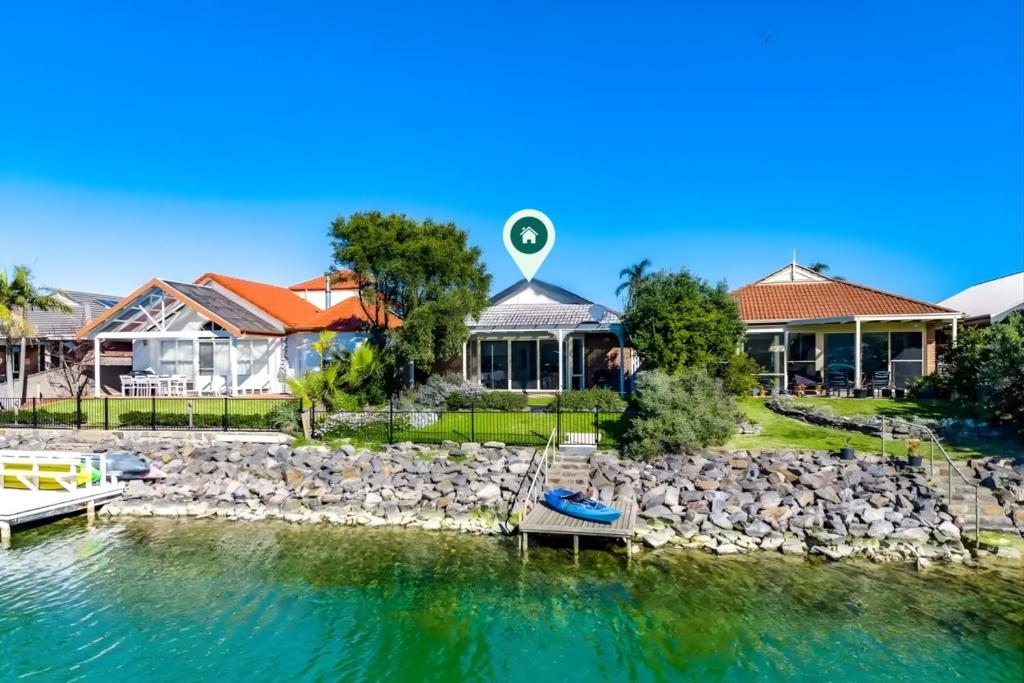 a house on the water with a boat in front at The Water House - Lakeside Serenity & Modern Comfort in Encounter Bay