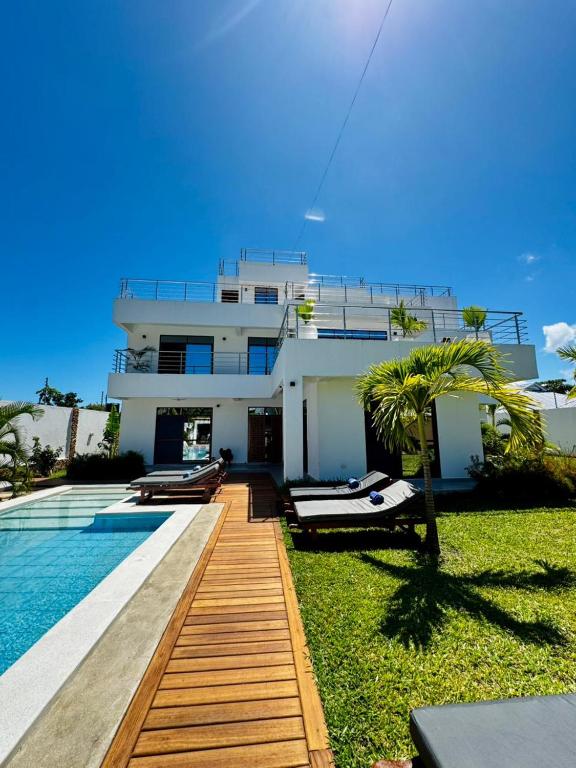a large white house with a swimming pool next to it at Villa Samara - 10p - 5bdr - Diani Beach - Piscine in Magutu