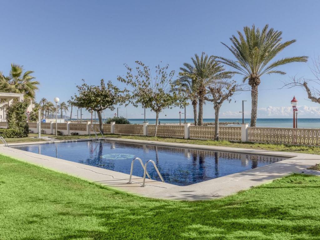 a swimming pool with palm trees and the ocean at Apartment Xaloc by Interhome in Cubelles
