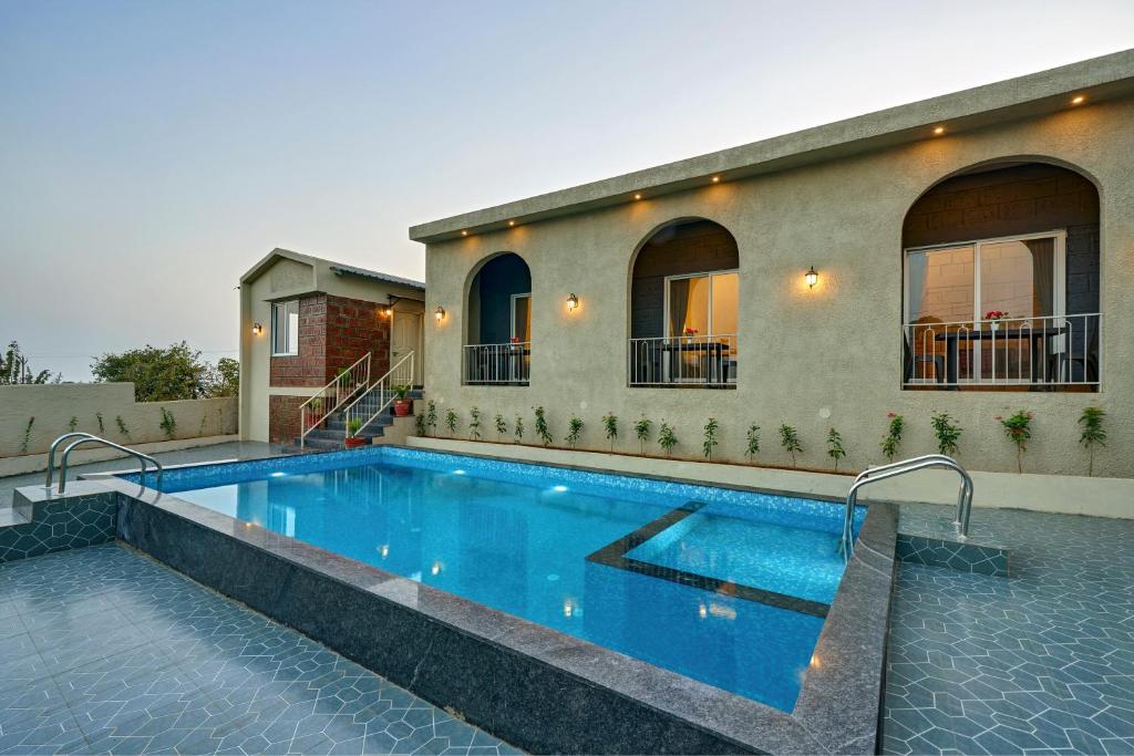 a swimming pool in front of a house at Breeze Resort Panhala , Swimming Pool, Just 5 Minutes From Panhala! in Panhāla