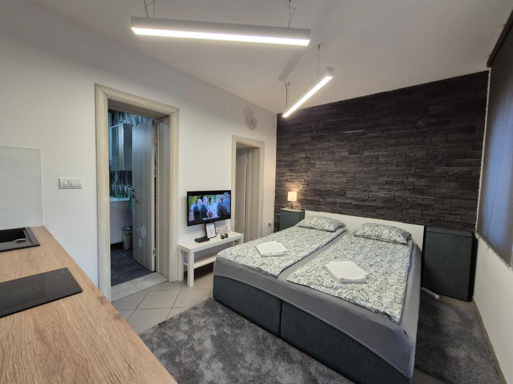 a bedroom with a large bed and a brick wall at Studio Apartman 47B in Valjevo
