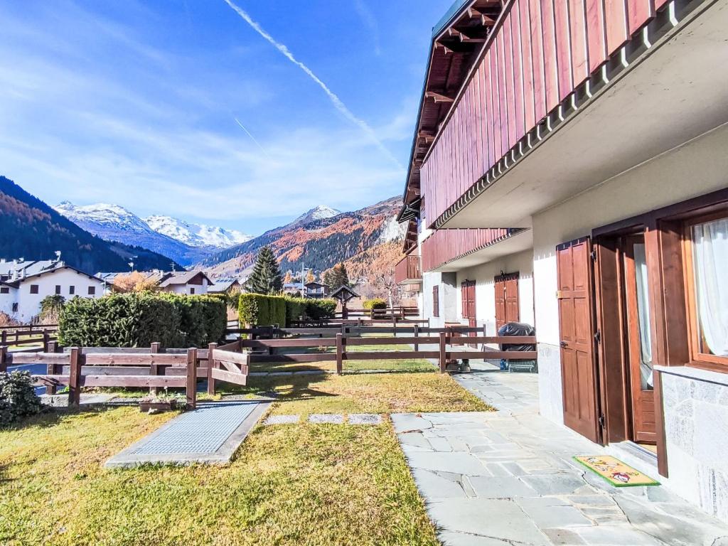 a building with wooden fences and mountains in the background at Apartment The Silent Sylva by Interhome in Isolaccia