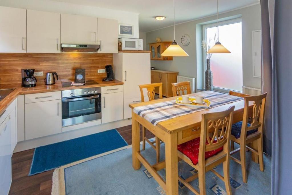 a kitchen with a wooden table with chairs and a dining room at Ferienhaus-Mackeriege in Norden