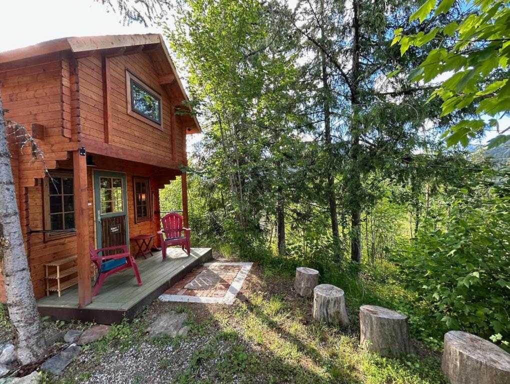 a log cabin in the woods with a porch and a chair at Funky Bunky in Nelson