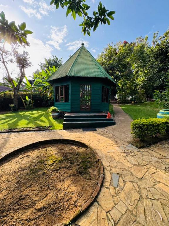 a small house with a green roof in a yard at Oldadai Falls Retreat in Arusha