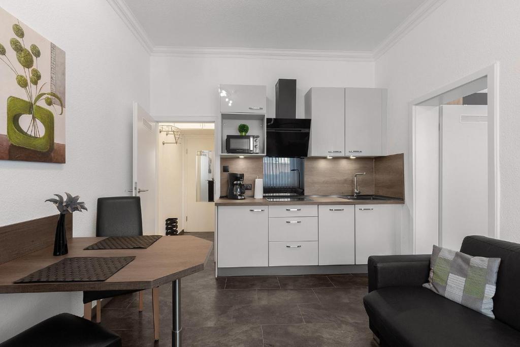 a kitchen with white cabinets and a table in a room at Solymar Whg 11 in Grömitz