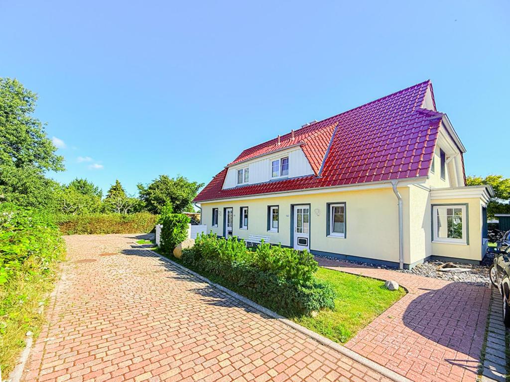 a house with a red roof on a brick driveway at Ferienhaus Kranichnest in Breege