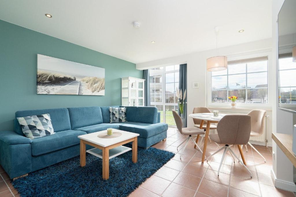 a living room with a blue couch and a table at Commodore Whg 15 in Grömitz