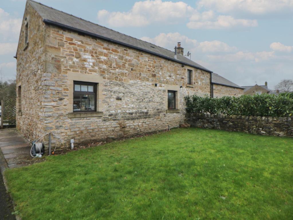 a brick building with a grass yard in front of it at Win Hill View Cottage in Hope