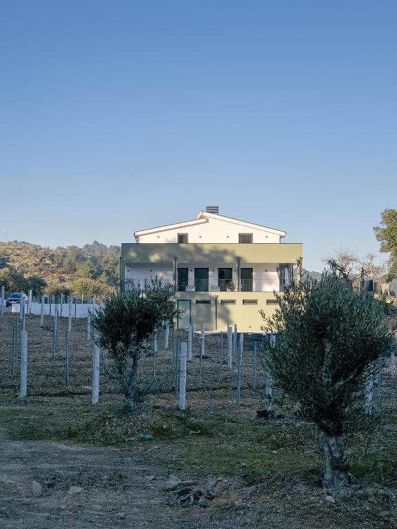 a house behind a fence with two trees at Raposa Verde - Agroturismo in Pegarinhos