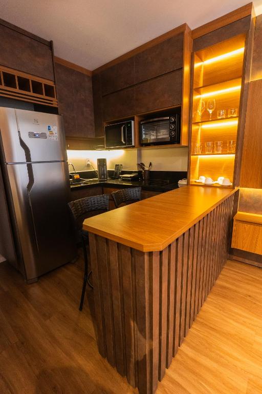 a kitchen with a refrigerator and a wooden counter at Flat exclusivo Studio Cuiabá 908 in Cuiabá