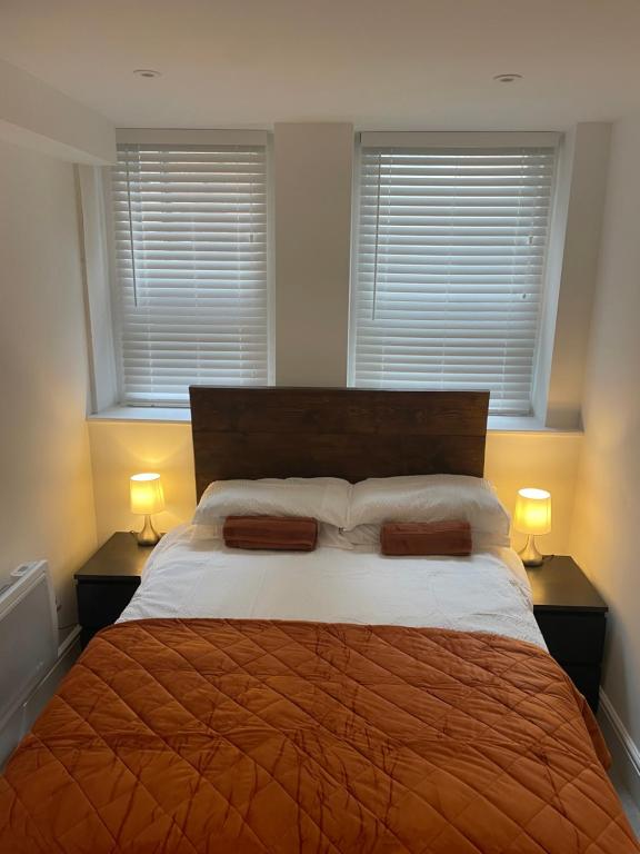 a bedroom with a large bed and two windows at Weymouths Coastal Nook in Weymouth