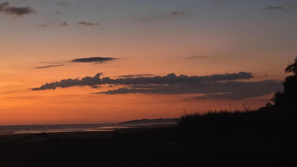 a sunset on a beach with the ocean at HOUSEWAVe in Parrita