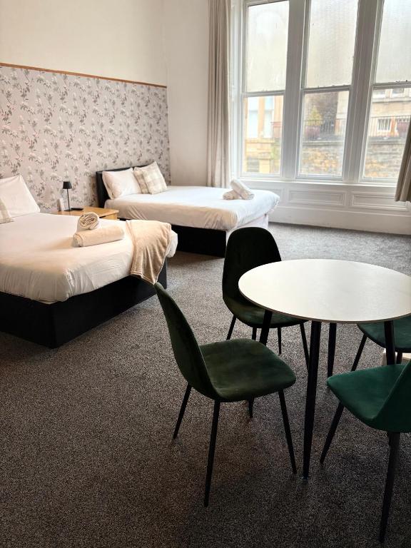 a room with two beds and a table and chairs at Piccolo in Glasgow