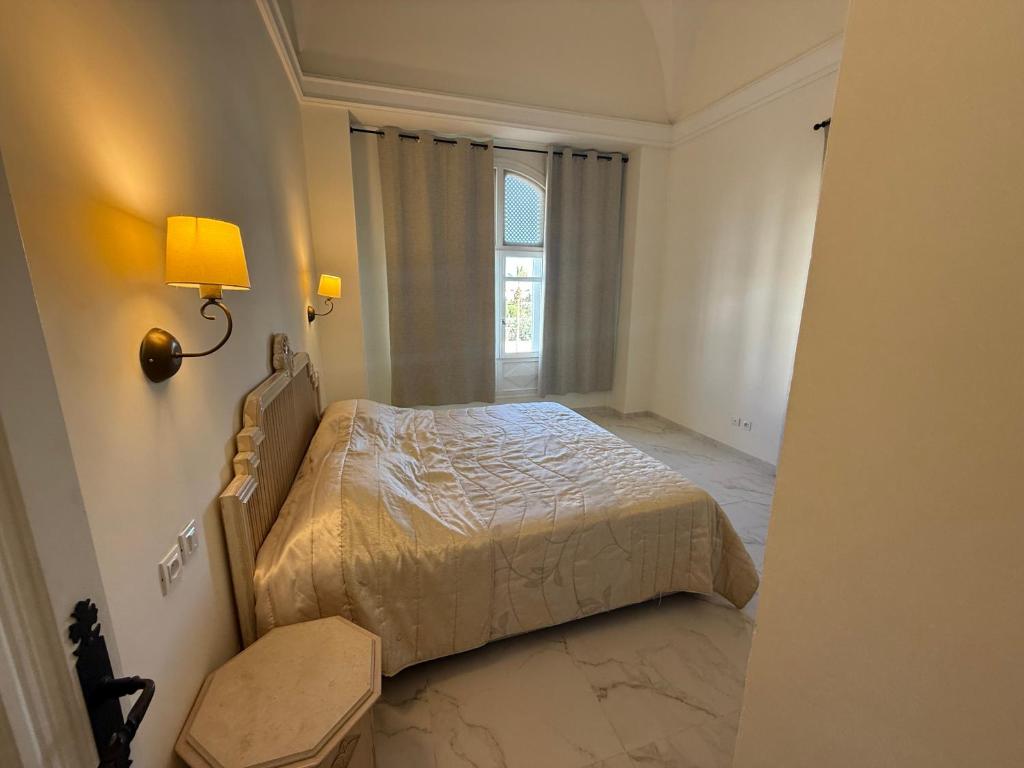 a bedroom with a bed and a lamp and a window at Yocca Hotel Residence in Hammamet