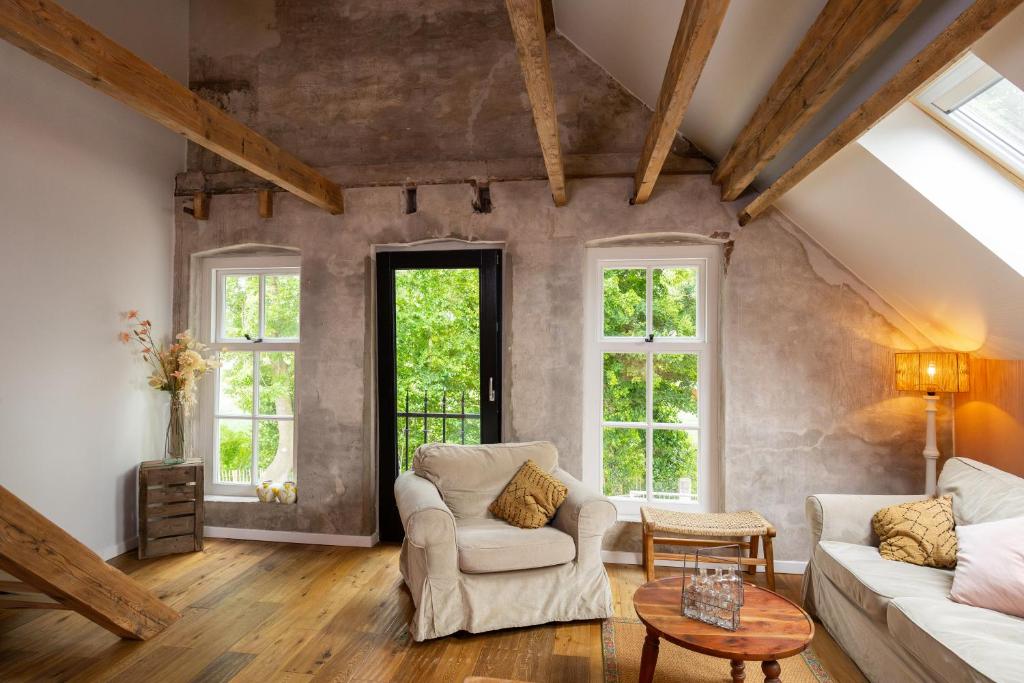 a living room with two couches and two windows at Bed & Breakfast De Tol in Sint Annaland