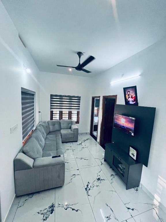 ein Wohnzimmer mit Sofa und Flachbildfernseher in der Unterkunft Stay loop in Cherambādi