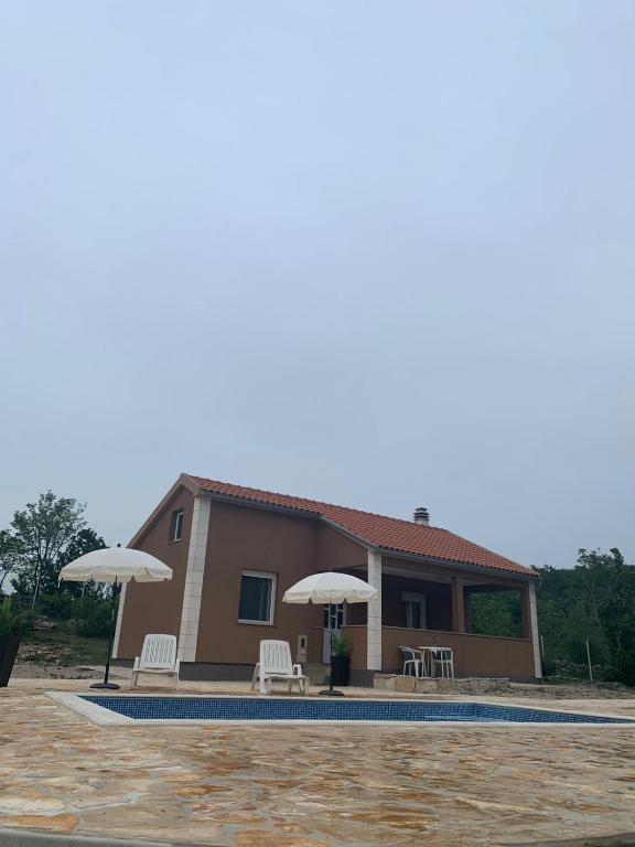 a house with a pool and two umbrellas at Villa Julija with Private Pool in Bilišane