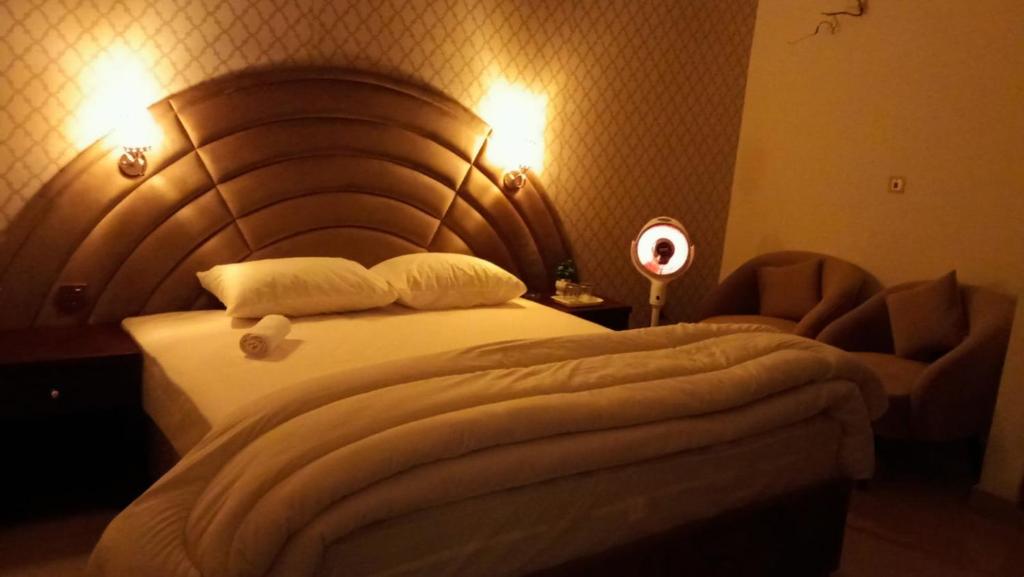 a bed in a hotel room with a wooden headboard at Royalz Hotel in Lahore