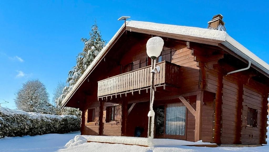 a log cabin with a balcony in the snow at Chalet Des Charmes in Thollon