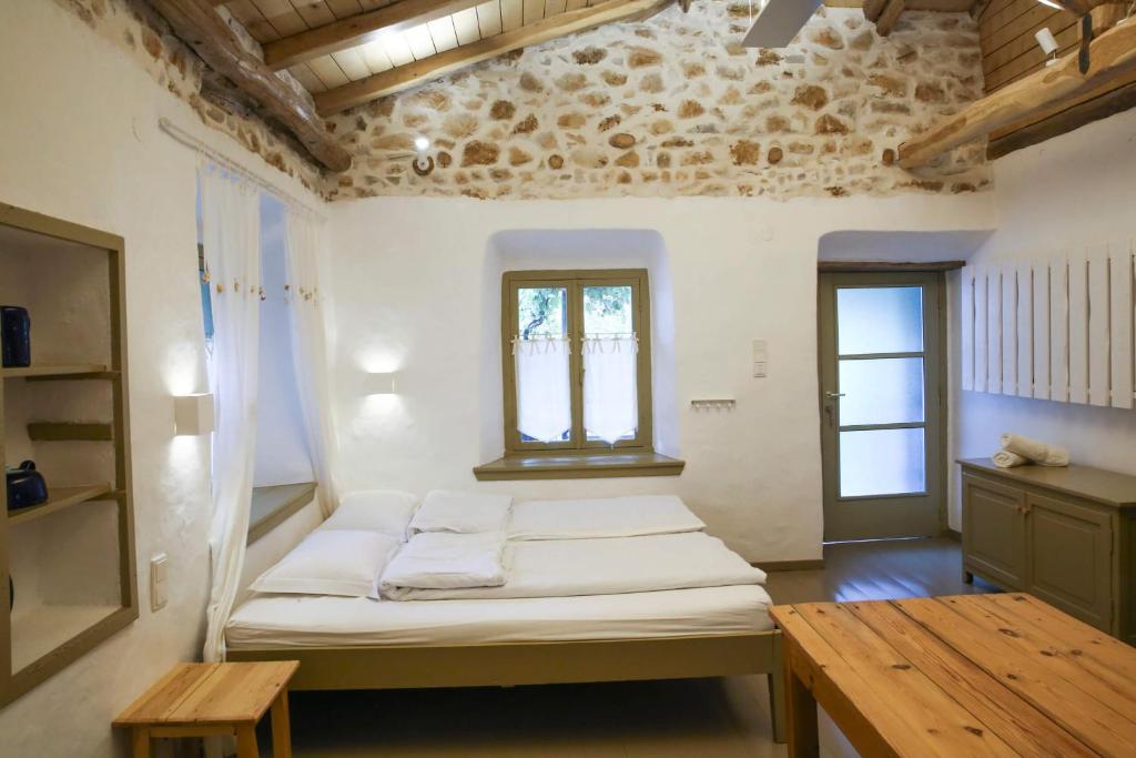 a room with a bed and a window and a table at Ghermaniko Guesthouse in Damouchari