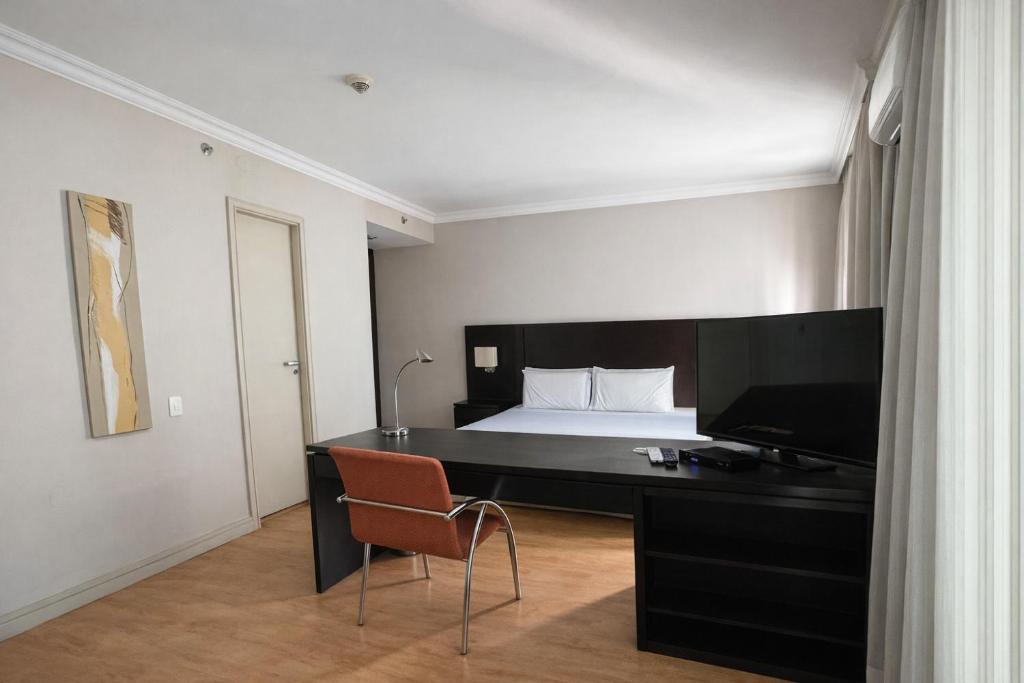 a bedroom with a bed and a desk with a television at Flat em Perdizes, perto da PUC e Allianz Parque in São Paulo