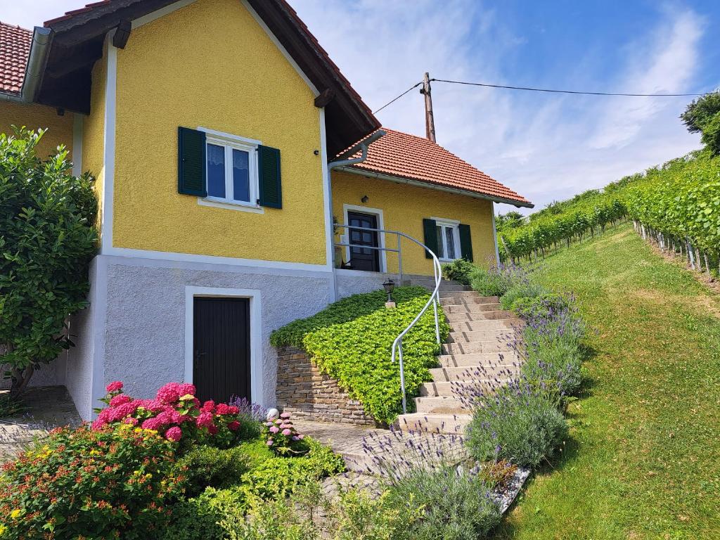 a yellow house with some flowers in front of it at Ferienhaus Weingut Bauer in Gamlitz