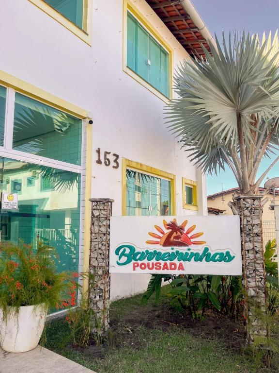 a sign in front of a building with a palm tree at Pousada Barreirinhas in Barreirinhas