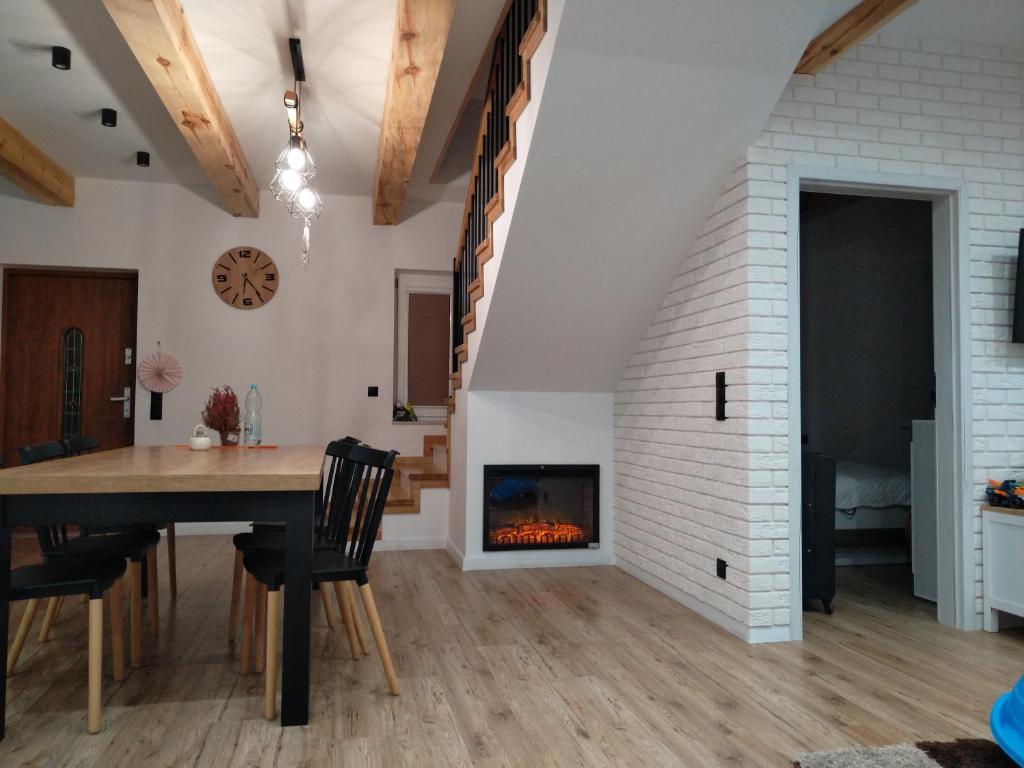 a dining room and living room with a fireplace at Domek NAD RZEKA in Korczew