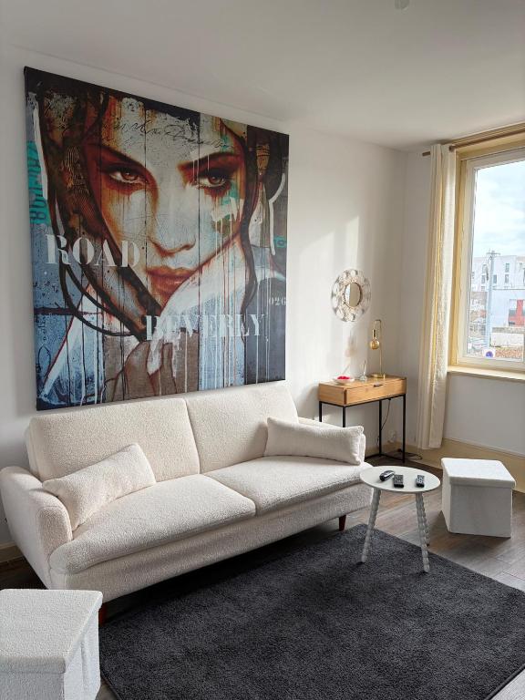 a living room with a white couch and a painting on the wall at Petit appartement charmant in Lille